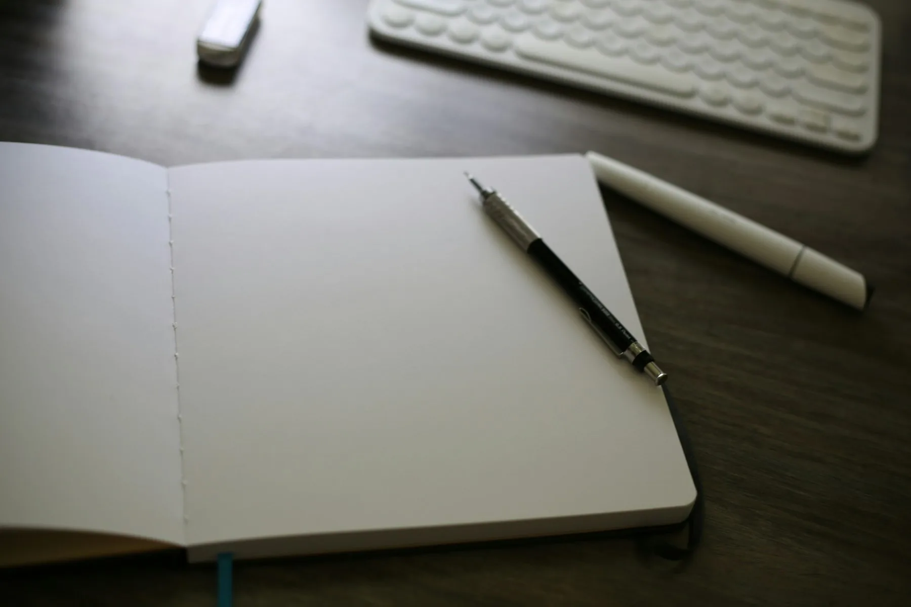 Cuaderno abierto y lápiz junto a un teclado