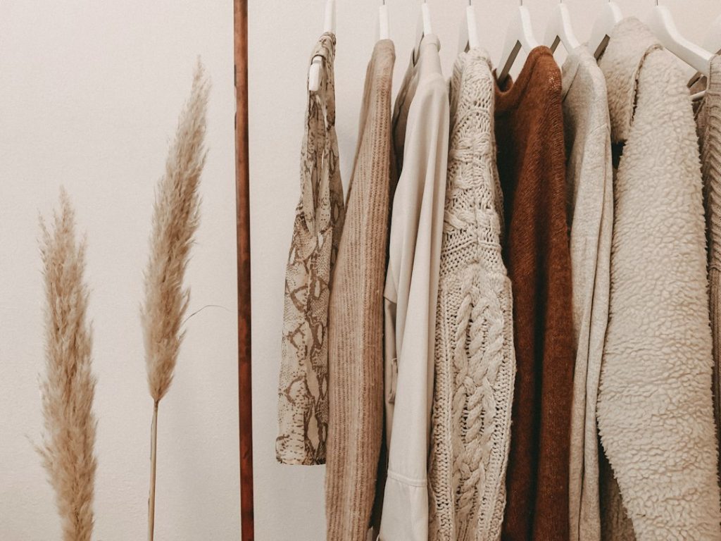 Prendas en tonos crema, beige y marrón organizadas en perchas sobre un perchero