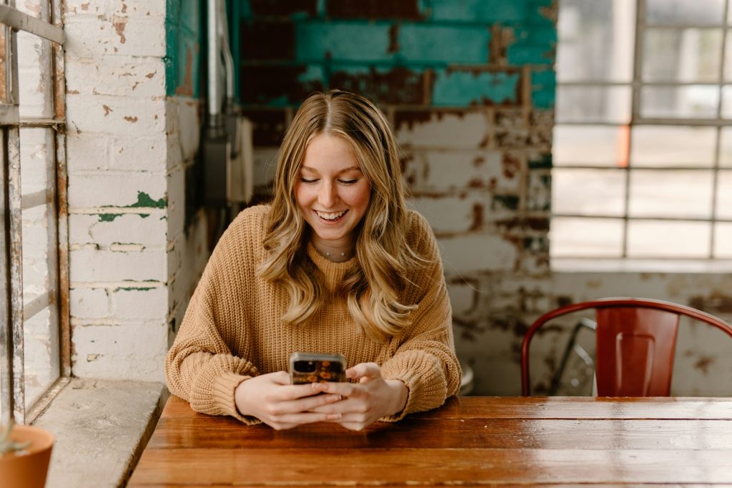 Mujer consultando su teléfono en una mesa de madera de una cafetería
